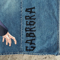 Close-up of Y2K Anime Baggy Jeans featuring hand illustration and bold "CABRERA" text on denim fabric.