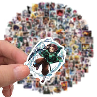 A mixed pack of waterproof Demon Slayer Stickers featuring cute Tanjiro and Nezuko anime art, applied to a laptop and phone case.
